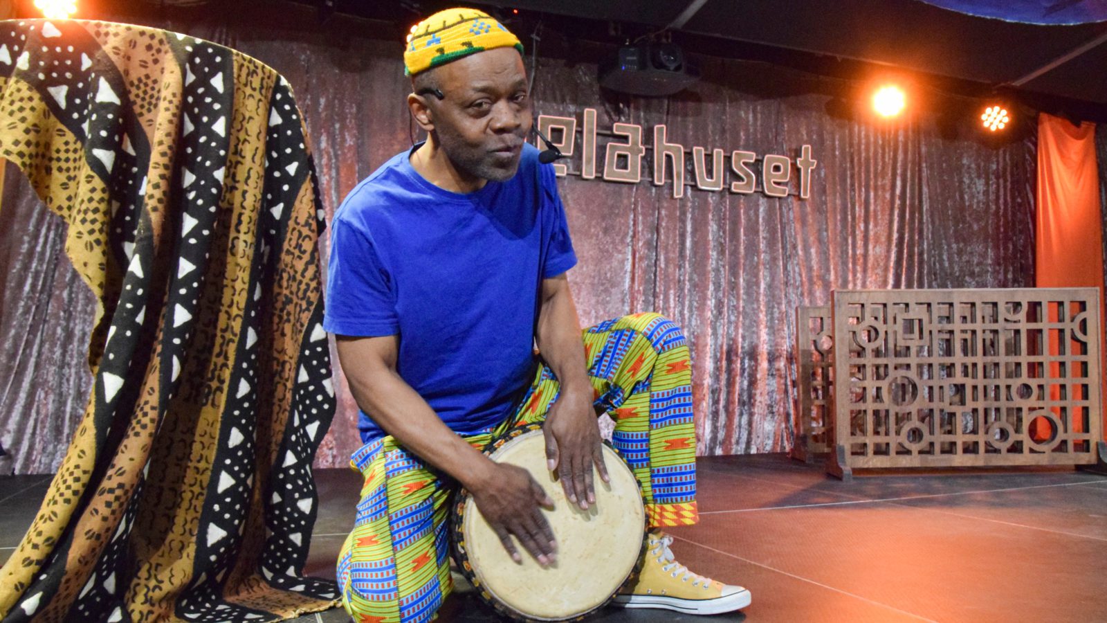 Raymond Sereba on stage playing a djembe.