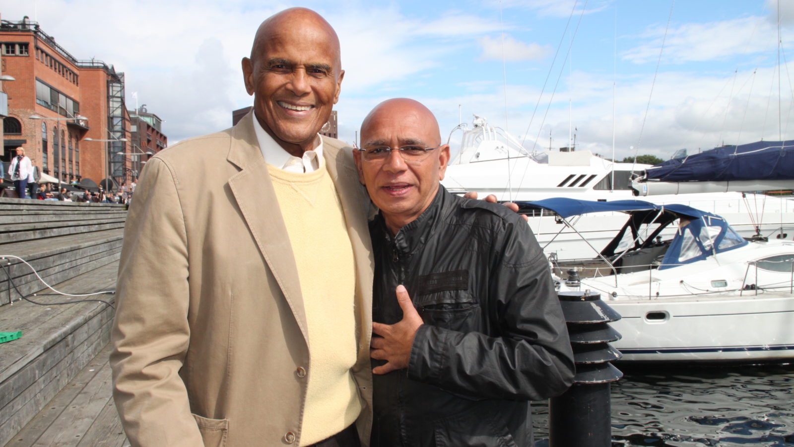 Two people arm in arm with a boat in the background