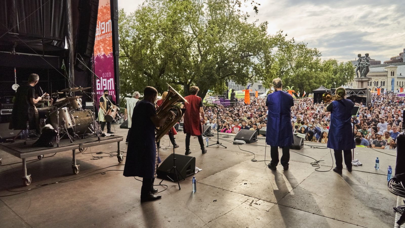 Bollywood Brass Band on stage. The band stands with their backs turned and looks out over the audience